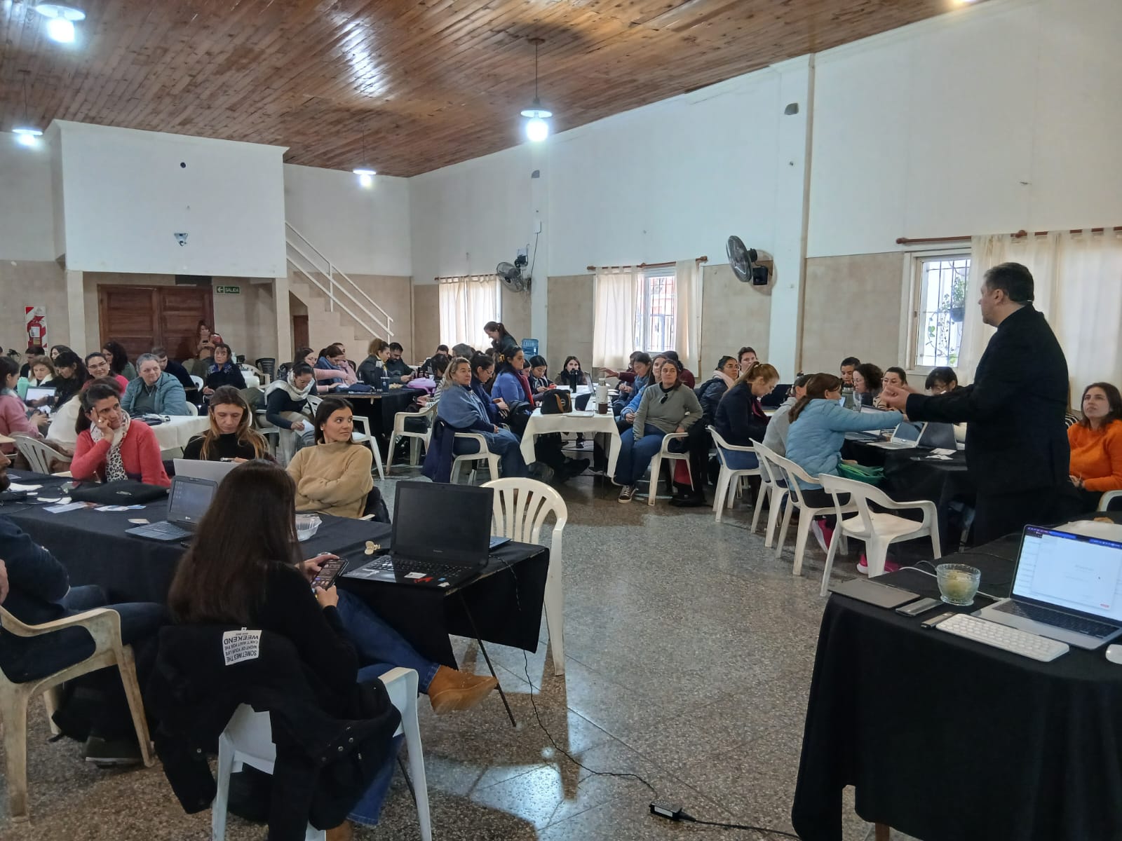 Taller de formación con profesionales trabajando en mesas y Gastón Sánchez acompañando la actividad